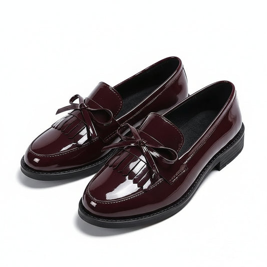 Pair of burgundy loafers with tassels on a white background