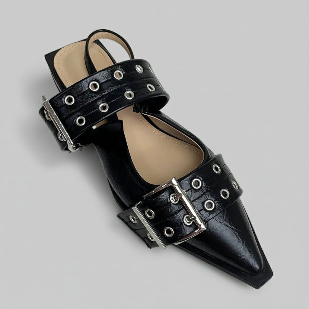 Black pointed-toe shoe with metallic buckles on a light gray background